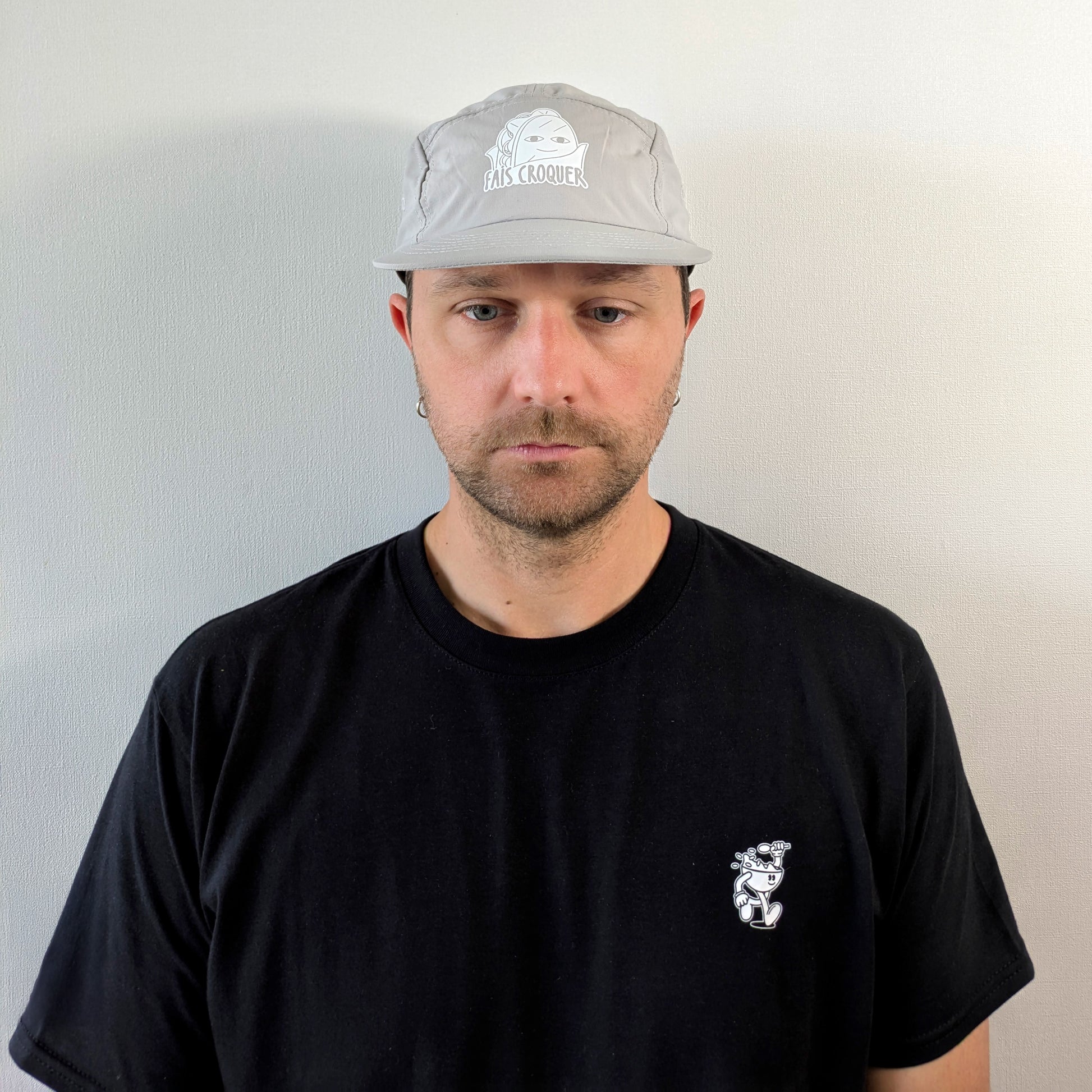 Homme portant la casquette beige Fais Croquer, look casual avec t-shirt noir à motif food vintage